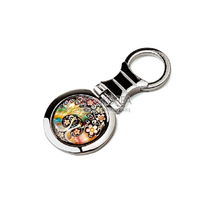 자개 상감 기법으로 공작과 꽃문양을 표현한 원형 장식, 은빛 금속 테두리의 열쇠고리.