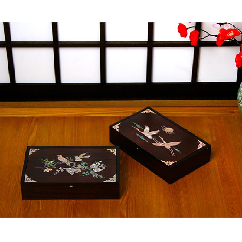 어두운 옻칠 표면에 자개 상감으로 매화와 새, 학과 해 문양을 넣은 직사각 메모함.