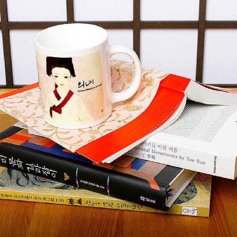 백색 세라믹 재질에 붉은색·검은색 포인트의 의녀 일러스트와 한글 글씨가 인쇄된 머그컵. 백색 세라믹 재질에 붉은색·검은색 포인트의 의녀 일러스트와 한글 글씨가 인쇄된 머그컵.