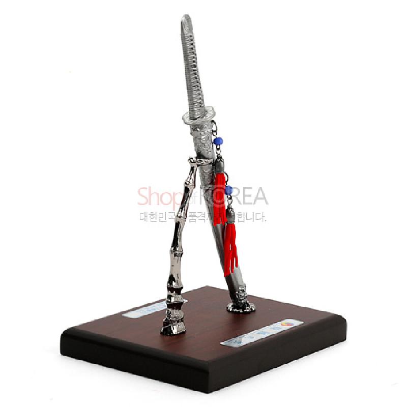 금속 재질의 한국도 모형과 검집, 붉은 술 장식이 어우러진 목재 받침대 장식.