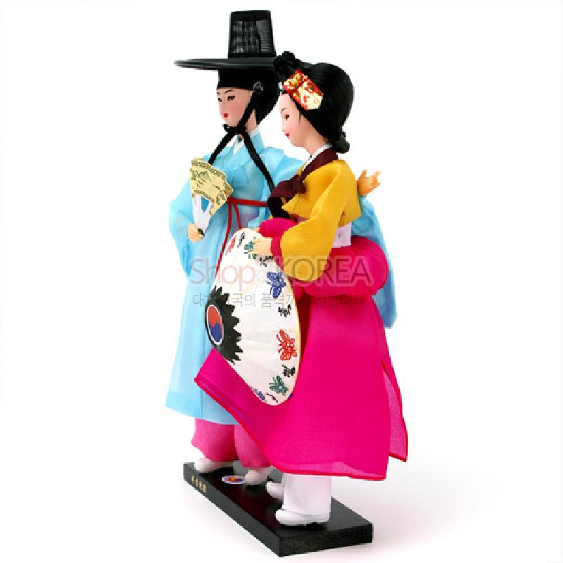 비단 한복 소재의 남녀 인형으로, 선비 갓과 부채, 화려한 자수 노리개와 태극·꽃문양 장식이 어우러진 전통 복식 인형.