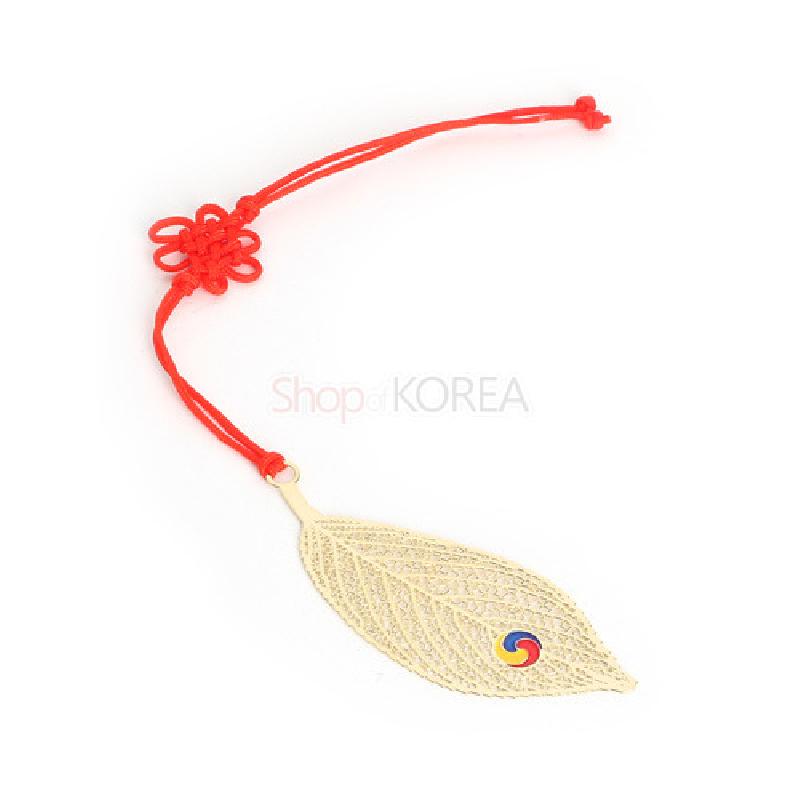 금장 금속으로 제작된 나뭇잎 모양 책갈피와 태극 문양 장식, 붉은색 전통 매듭끈이 어우러진 디자인.