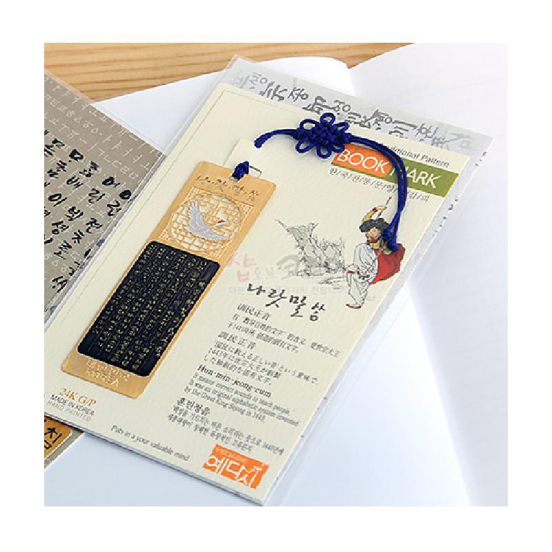 금속 재질에 한글 글귀와 학 문양을 음각한 책갈피, 청색 전통 매듭 끈 장식 구성의 세트 상품.