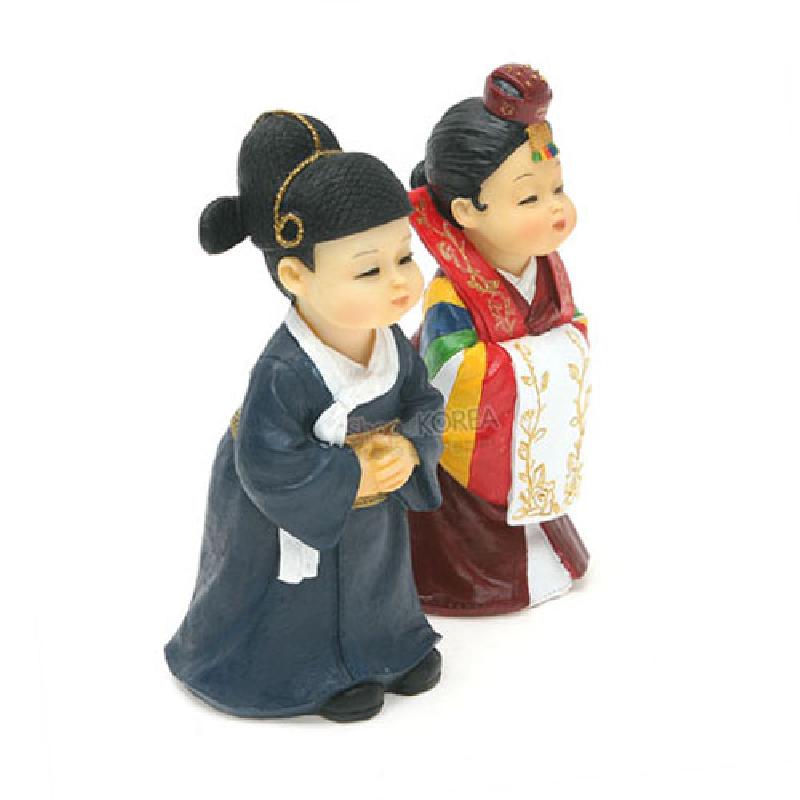 전통 혼례 한복을 입은 신랑신부 마블 인형으로, 남색 도포와 오색 동정, 금색 자수 문양의 활옷과 족두리 장식이 특징인 조형물.