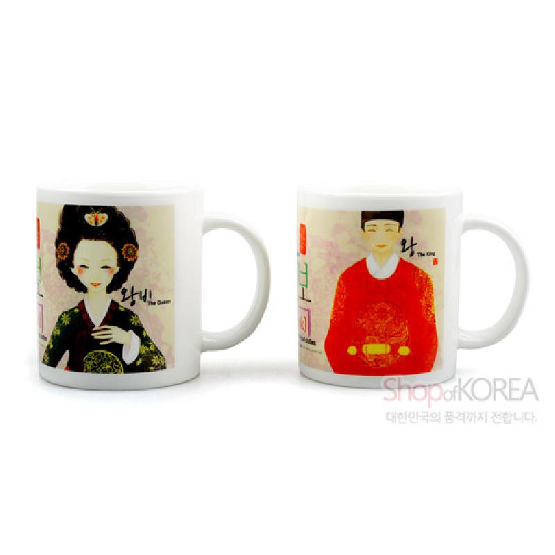 백색 도자 머그컵에 한국 전통 왕과 왕비를 현대적 일러스트로 표현한 디자인, 붉은색·녹색 한복과 은은한 배경 문양이 특징인 세트형 머그컵.
