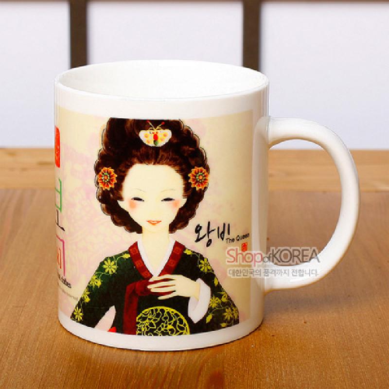 한국의 전통 왕비 복식 일러스트가 인쇄된 도자기 머그컵, 녹색과 적색 한복과 머리장식 문양이 특징인 디자인.