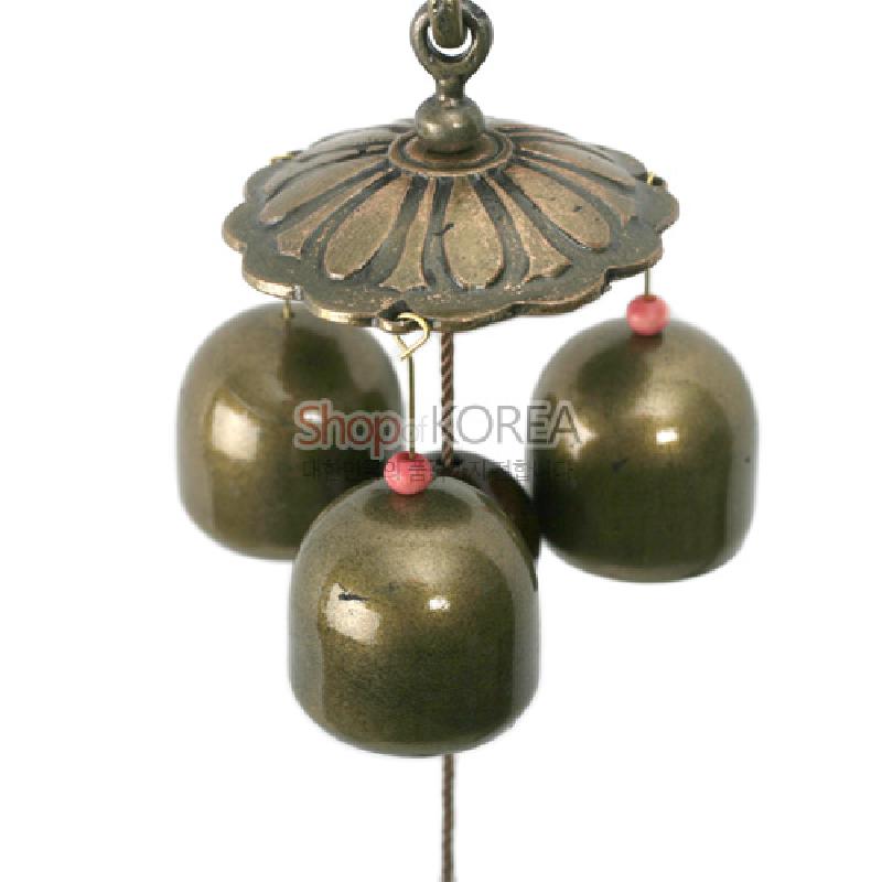 청동빛 금속 종 모양 장식과 연꽃형 금속 상부 장식, 분홍 구슬 포인트가 어우러진 복주머니 장식.
