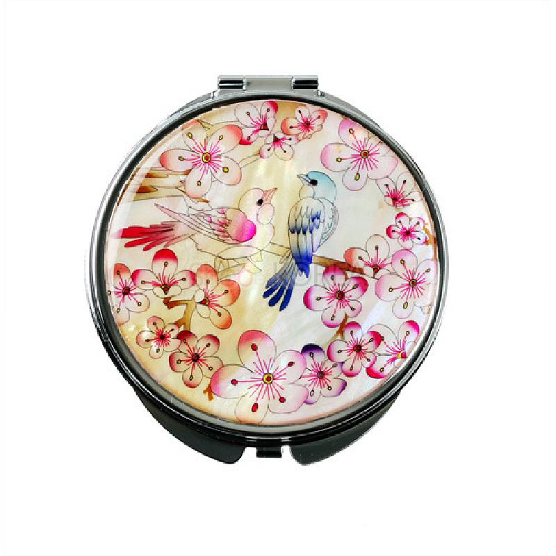 자개 바탕 위에 매화와 두 마리 새를 섬세한 채색으로 표현한 원형 손거울, 분홍·흰색 조화가 돋보임