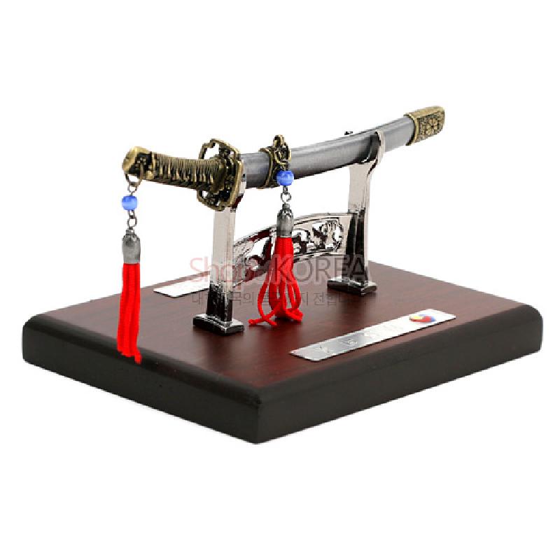 금속 재질 검신과 칼집, 조각 장식 거치대, 붉은 술과 청색 구슬 장식이 어우러진 스탠드형 모형 한국도.