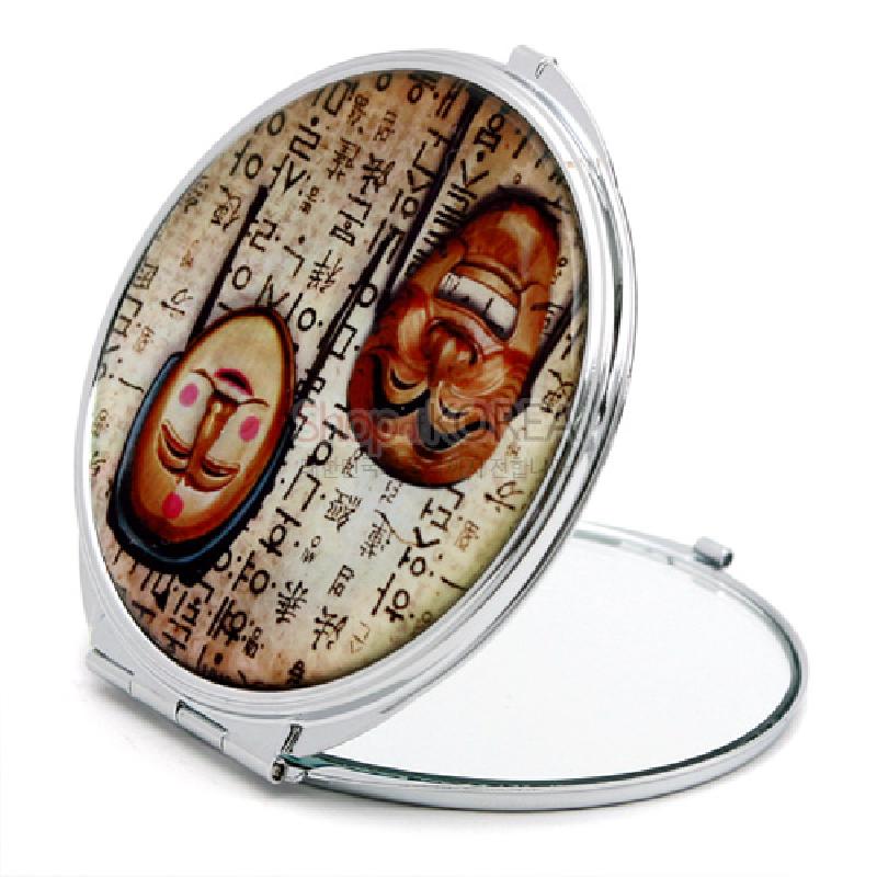 금속 테두리에 한지 느낌 배경과 하회탈 문양이 인쇄된 원형 접이식 손거울. 금속 테두리에 한지 느낌 배경과 하회탈 문양이 인쇄된 원형 접이식 손거울.