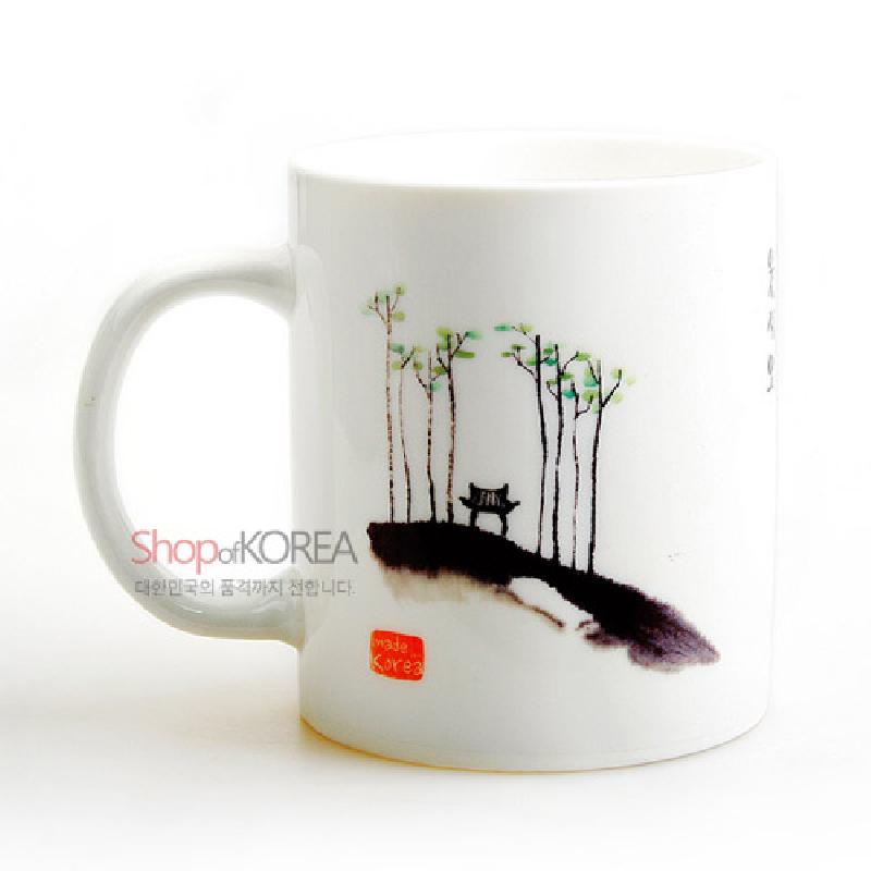 백자 머그컵에 수묵채색 기법으로 표현된 소나무 숲과 벤치 풍경 문양이 특징인 머그컵.