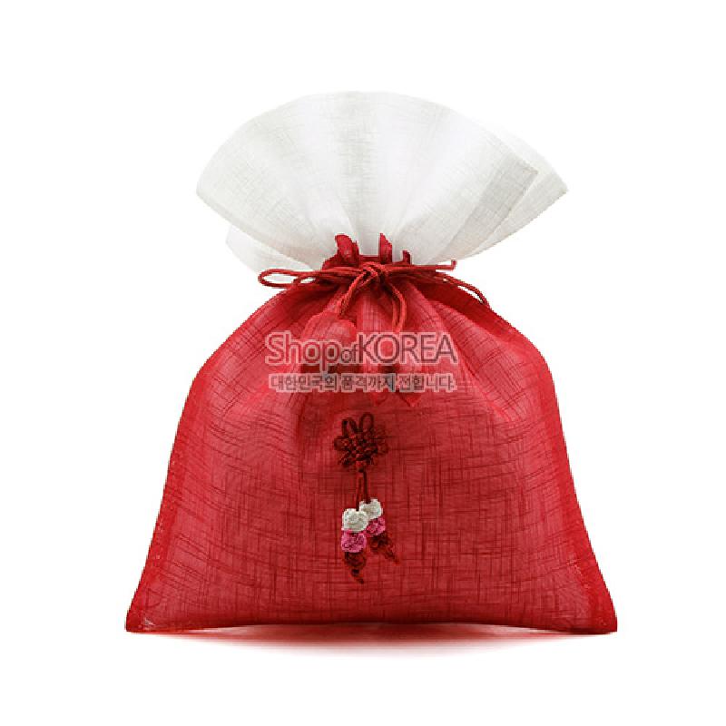 붉은 모시 천과 흰 모시 덮개로 구성된 복주머니, 중앙에 매듭 기법과 꽃 장식이 더해진 전통 주머니.
