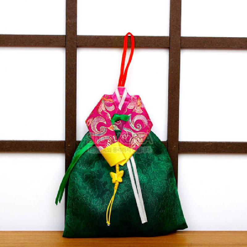 녹색 치마와 분홍 저고리 형태의 비단 향주머니, 금색 꽃무늬와 노랑 매듭 장식이 특징인 한복 모양 벽걸이.