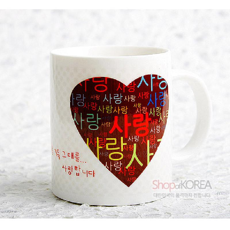 하얀 세라믹 재질에 붉은 하트형 배경과 다채로운 색상의 ‘사랑’ 한글 패턴이 인쇄된 머그컵.