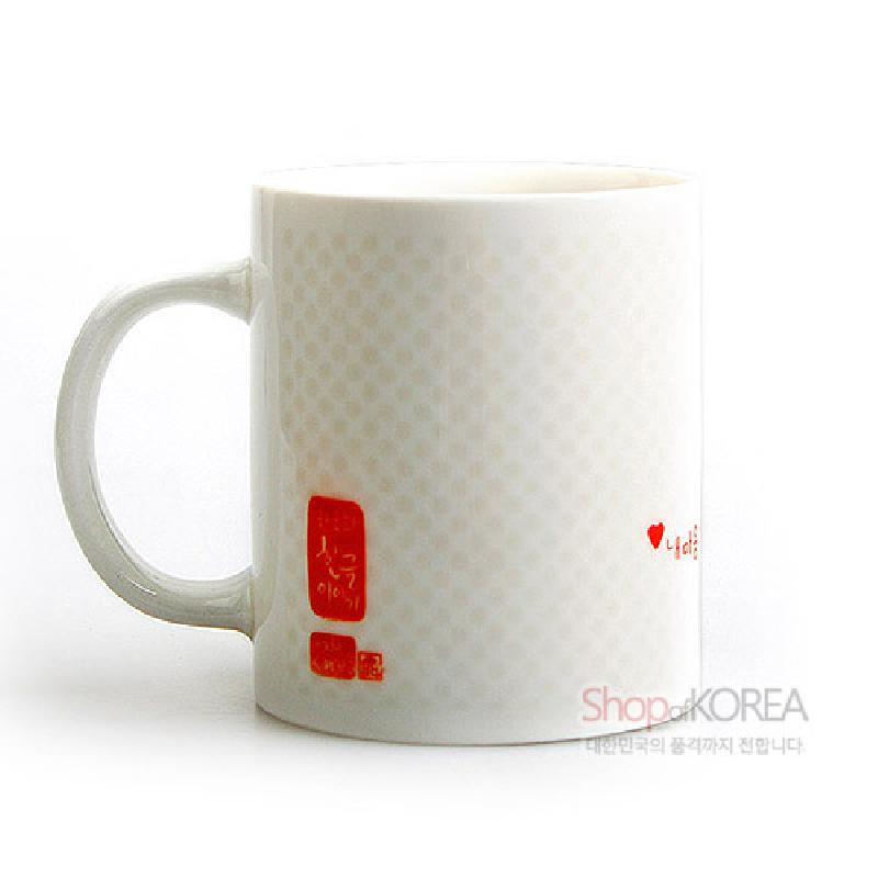백자 재질의 머그컵에 옅은 격자 문양과 붉은색 인장풍 한글 서체 포인트가 가미된 디자인.
