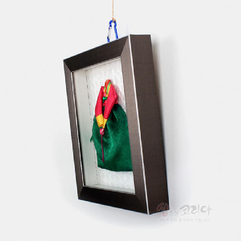 녹색 치마와 오방색 저고리 비단 한복 미니어처를 입체적으로 배치한 직사각형 벽걸이 액자형 장식.