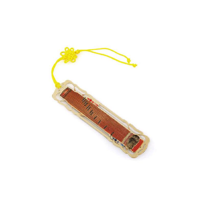 금장 처리된 금속 틀 안에 적갈색 가야금 문양이 배치되고 노란 전통 매듭 끈이 달린 책갈피. 금장 처리된 금속 틀 안에 적갈색 가야금 문양이 배치되고 노란 전통 매듭 끈이 달린 책갈피.