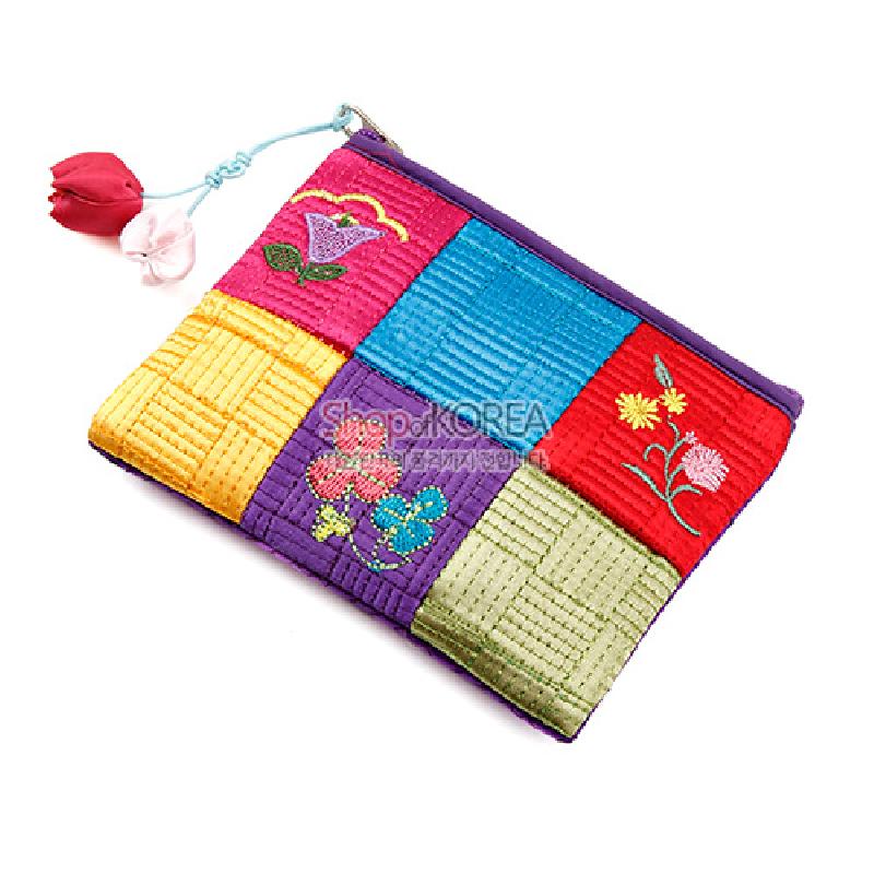 비단 재질의 누빔 바탕에 보라색 가장자리와 오방색 조각 배치, 꽃 자수 문양과 매듭 장식이 어우러진 동전지갑. 비단 재질의 누빔 바탕에 보라색 가장자리와 오방색 조각 배치, 꽃 자수 문양과 매듭 장식이 어우러진 동전지갑.