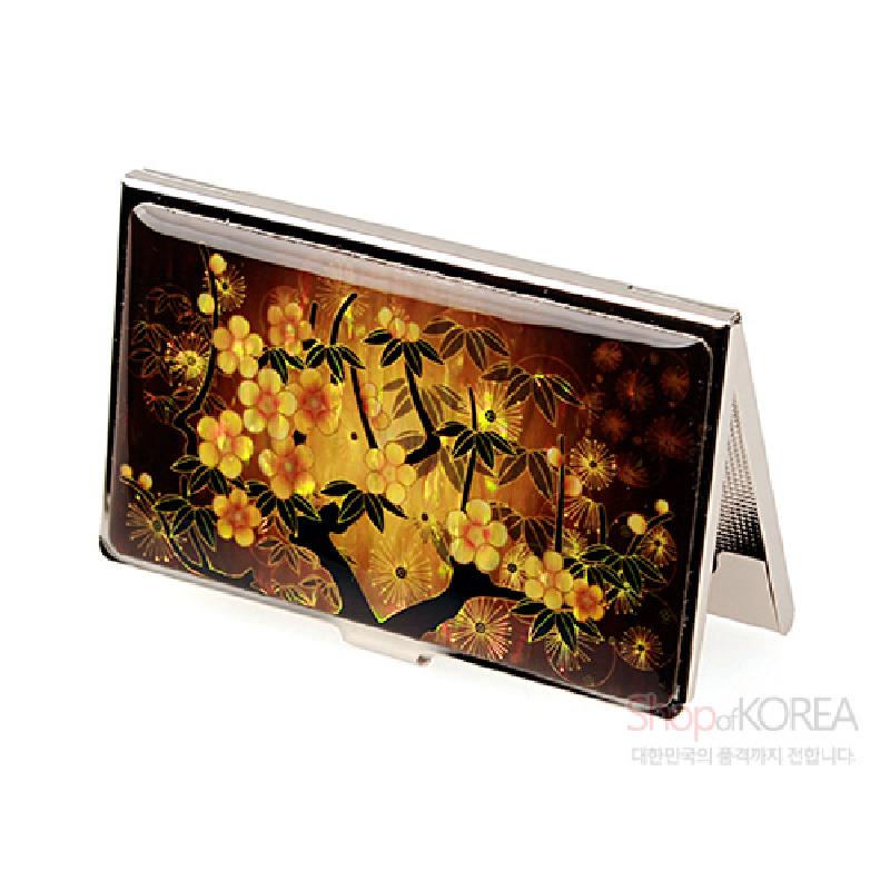 황색 그라데이션 배경 위에 매화와 잎사귀 문양이 그려진 금속 테두리 명함케이스.