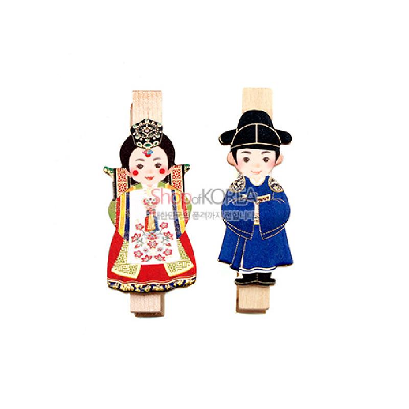 나무 집게에 전통 혼례 한복 신랑신부를 형상화한 일러스트 장식, 붉은색·청색 대비와 문양 포인트가 돋보이는 메모자석 집게.