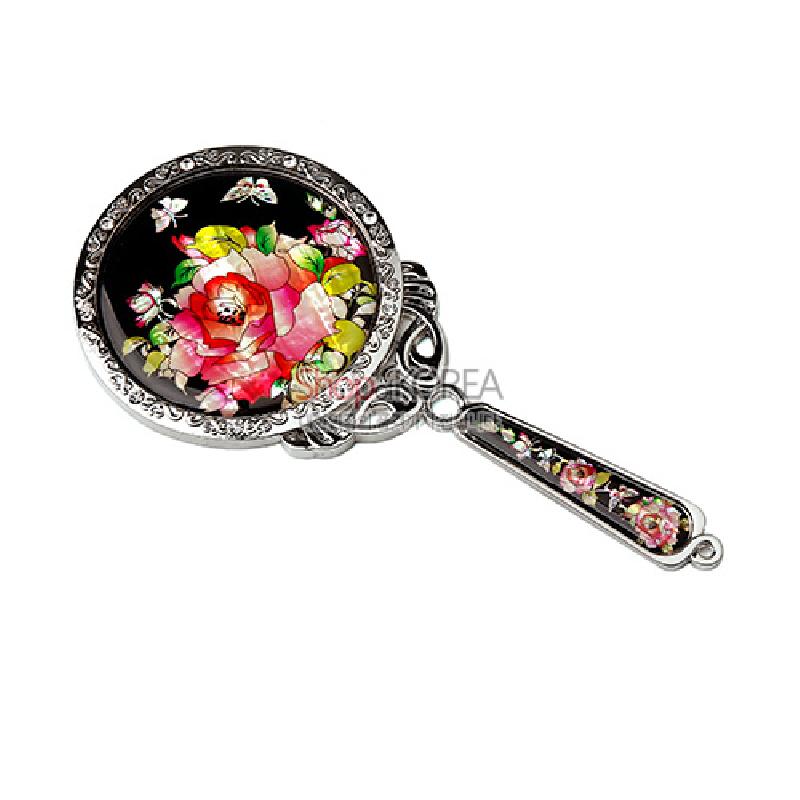 검은 옻칠 바탕 위 자개 상감으로 표현된 장미와 나비 문양, 금속 테두리와 손잡이 장식이 어우러진 주머니 손거울.