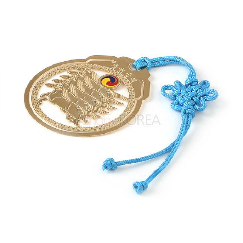 금장 메탈로 된 마패 모양 책갈피와 태극 문양 장식, 하늘색 전통 매듭 끈 장식의 디자인.