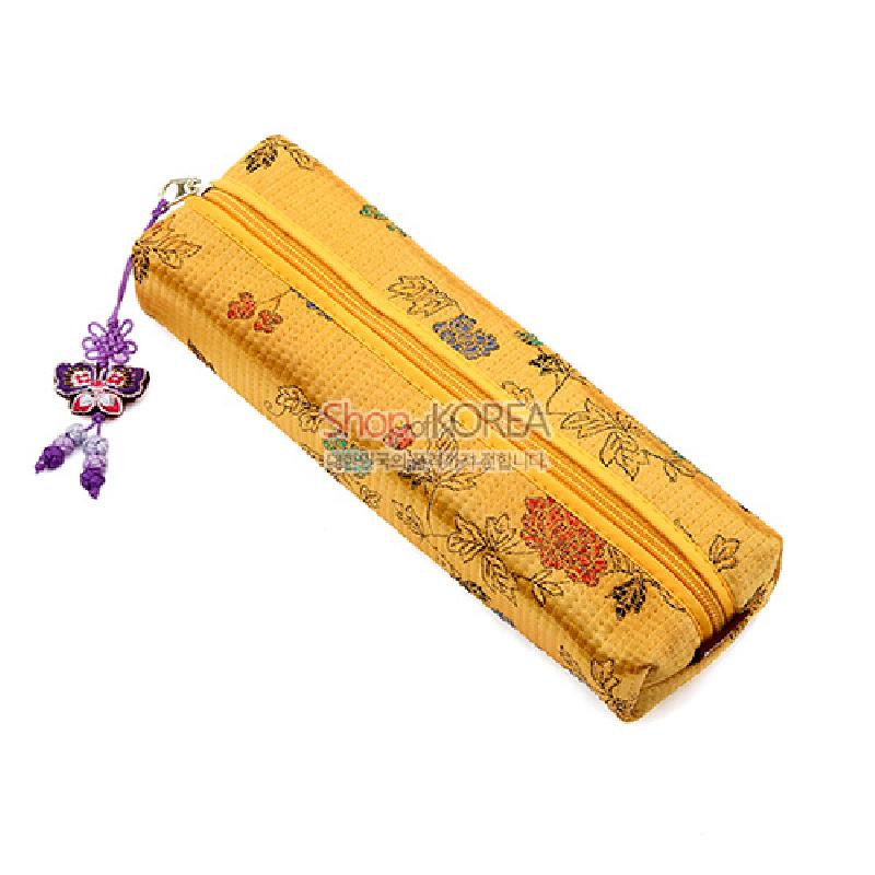황색 누비 비단에 꽃과 잎사귀 문양이 수놓인 원통형 필통, 나비 모양 매듭 장식 지퍼 장식.