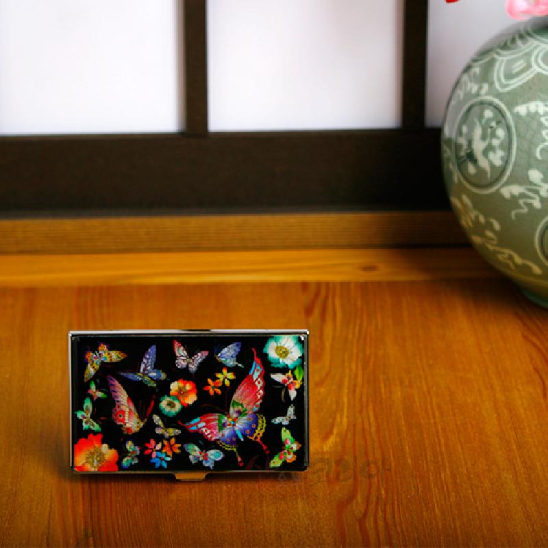 검은 바탕 위 자개 상감 기법으로 표현된 호랑나비와 꽃 문양, 금속 테두리가 조화를 이룬 명함케이스. 검은 바탕 위 자개 상감 기법으로 표현된 호랑나비와 꽃 문양, 금속 테두리가 조화를 이룬 명함케이스.