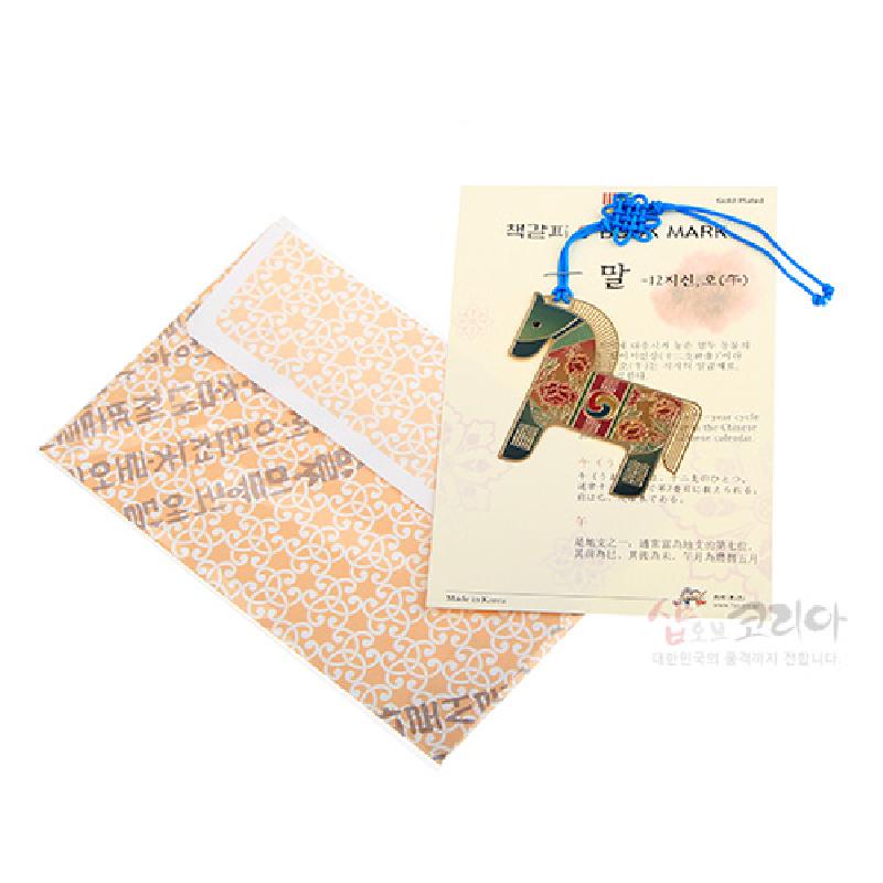 금빛 금속 재질에 오방색 전통 문양을 채운 말 형상 책갈피와 청색 매듭 끈 장식.