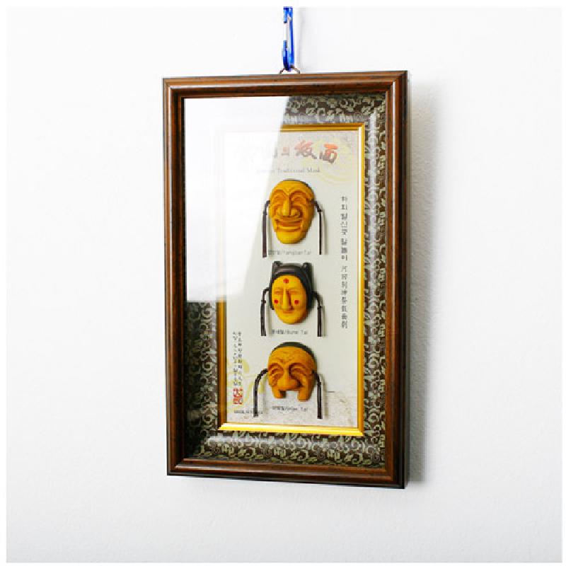 나무 재질로 표현한 노란색 하회탈 3형 입체 장식을 세로로 배치한 액자, 전통 문양 테두리와 갈색 나무 프레임이 특징인 장식품. 나무 재질로 표현한 노란색 하회탈 3형 입체 장식을 세로로 배치한 액자, 전통 문양 테두리와 갈색 나무 프레임이 특징인 장식품.