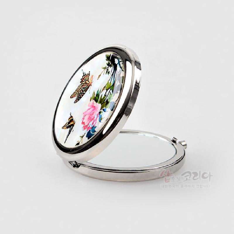 자개로 장식된 금속 프레임 원형 손거울, 흰 바탕 위에 담화와 나비 문양의 다채로운 채색이 돋보이는 디자인.