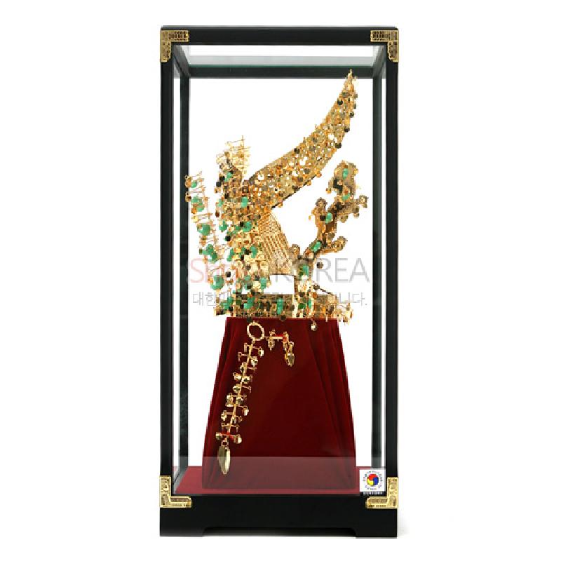 금속 재질로 제작된 금관 모형과 드리개 장식, 유리 케이스와 붉은 천 받침대가 조화를 이루는 장식품.