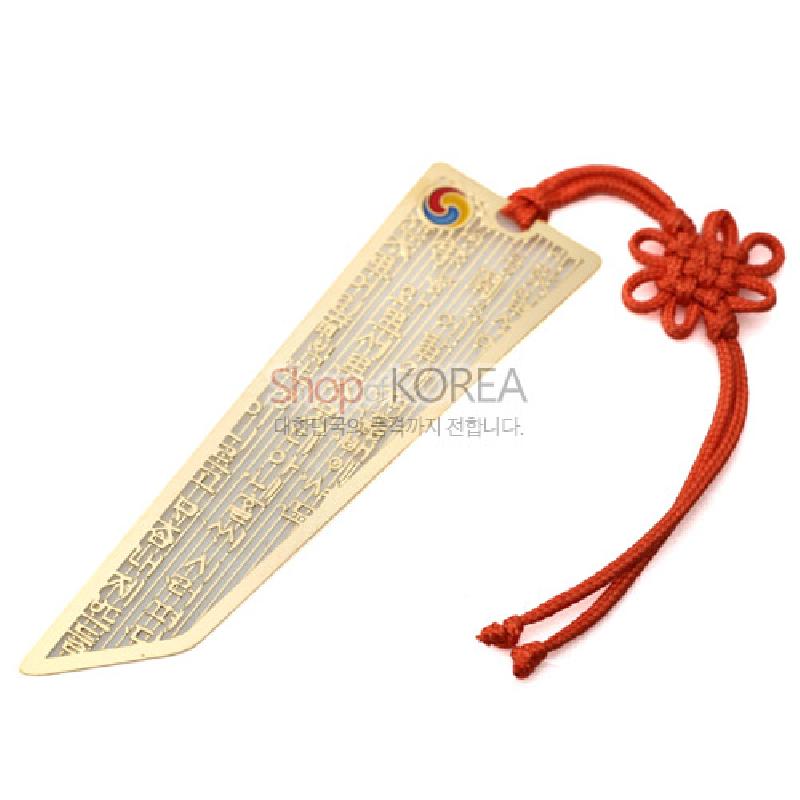 금속 재질에 훈민정음 글귀를 정교하게 음각한 책갈피와 태극 문양, 붉은 전통 매듭 끈 장식. 금속 재질에 훈민정음 글귀를 정교하게 음각한 책갈피와 태극 문양, 붉은 전통 매듭 끈 장식.