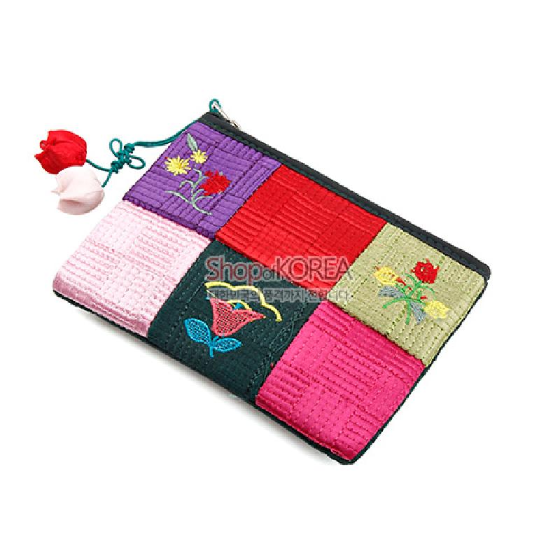 색색의 누빔 천을 조각보 형태로 배치하고 꽃 자수 문양을 수놓은 지퍼형 동전지갑.