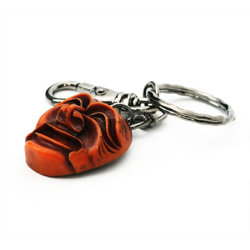 주황빛 양반탈 형태의 조각 장식과 은색 금속 체인, 고리로 구성된 열쇠고리.