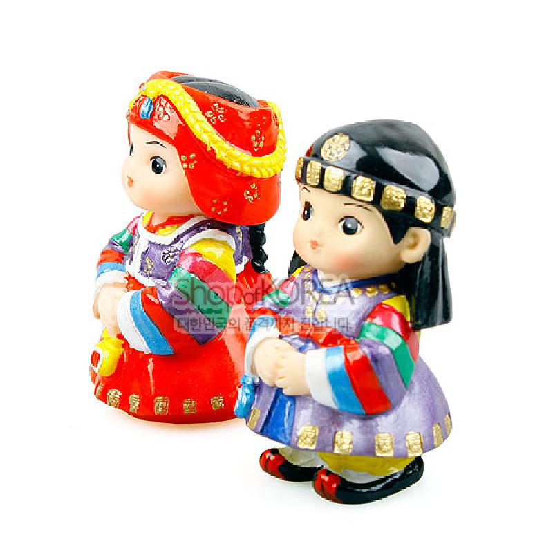 색동 줄무늬 한복과 붉은 치마, 금색 장식 머리쓰개가 특징인 도자 재질 설빔 민속인형 세트.
