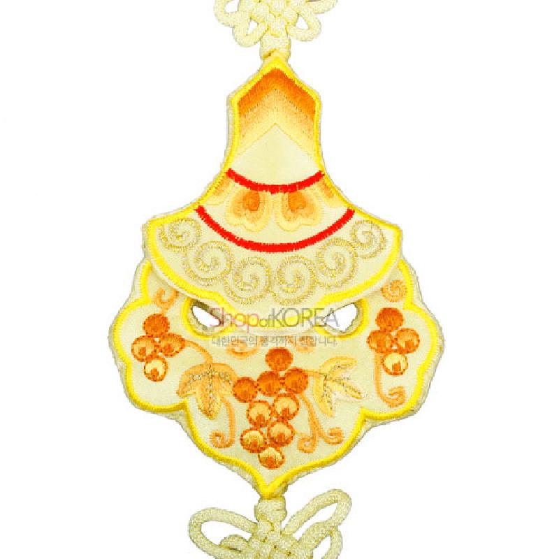 황색 비단 바탕에 오렌지색 포도 문양 자수로 장식하고 상단과 하단에 전통 매듭을 더한 노리개 장식. 황색 비단 바탕에 오렌지색 포도 문양 자수로 장식하고 상단과 하단에 전통 매듭을 더한 노리개 장식.