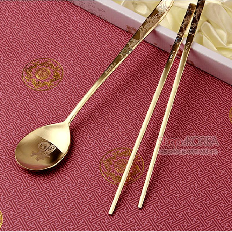 티타늄 재질의 황금빛 수저와 젓가락 세트, 용 문양과 전통 문양 각인 장식이 돋보이는 디자인.