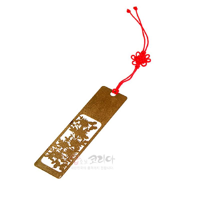 금속 재질의 금장 마감에 국화 문양을 섬세한 투각 기법으로 표현하고, 붉은 전통 매듭 끈 장식이 더해진 책갈피.