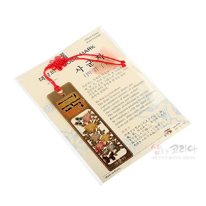금속 재질에 국화와 꽃문양을 세밀하게 양각한 금장 책갈피, 붉은 전통 매듭 장식 끈이 연결된 디자인.