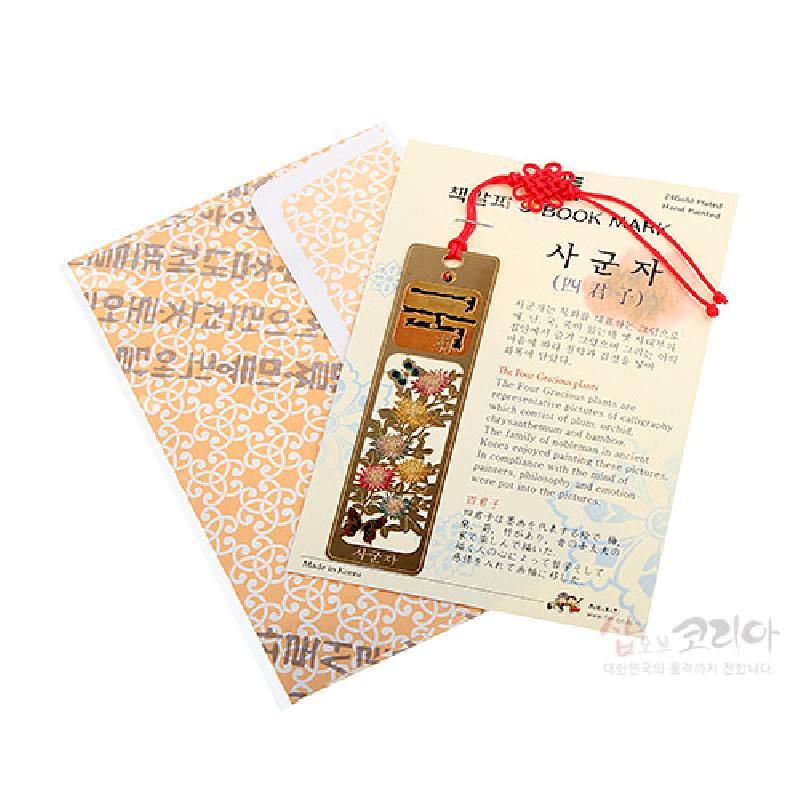 금장 금속 소재에 국화와 사군자 문양을 섬세하게 채색한 책갈피, 붉은 매듭 끈 장식이 특징인 디자인.