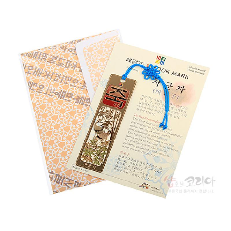 금속 재질에 대나무와 새 문양을 채색한 직사각 책갈피, 붉은 한자와 파란 전통 매듭 장식이 더해진 디자인.
