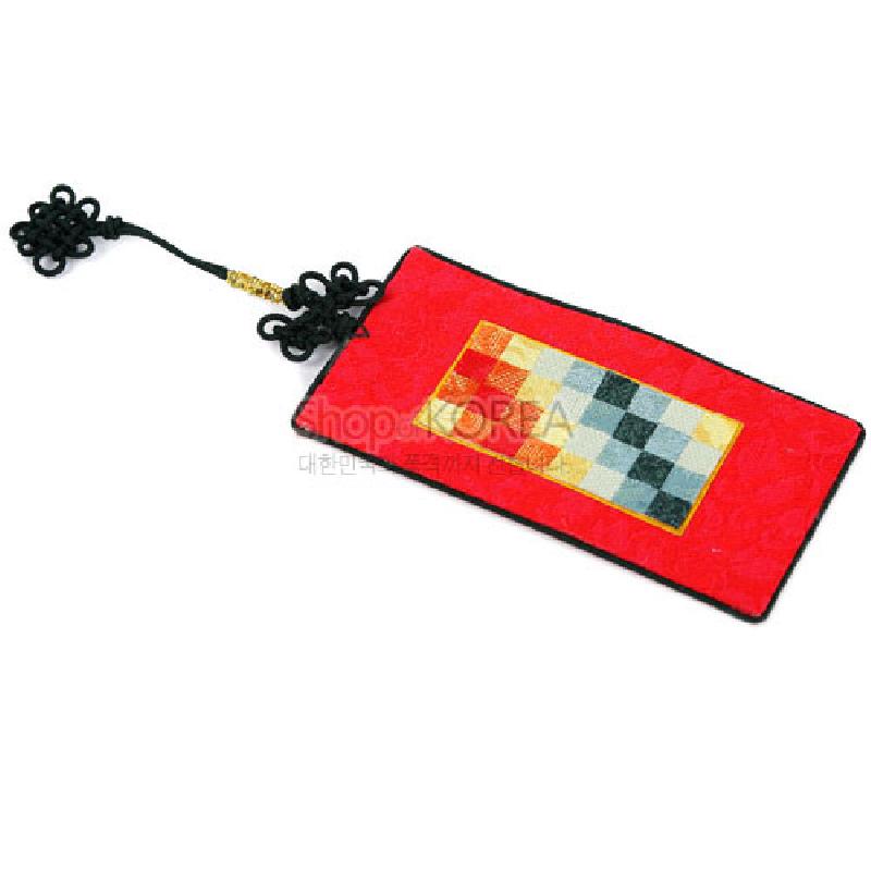 붉은 비단 바탕 위에 다색 조각보 패치워크를 넣은 직사각 책갈피와 흑색 전통 매듭 장식.