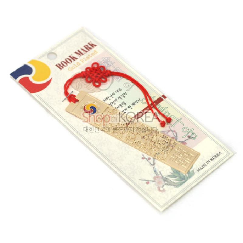 금장 금속 재질에 당초문과 전통 기하문양이 정교하게 음각된 책갈피, 상단 태극 문양과 붉은 전통 매듭 장식.