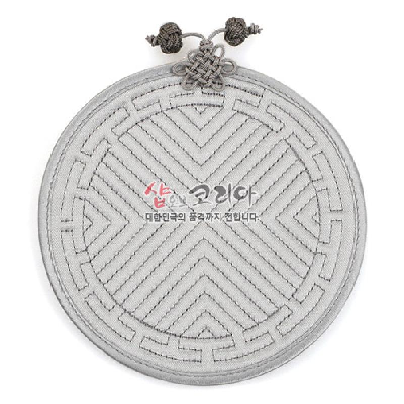 연회색 패브릭 누비 기법으로 사선과 기하학 무늬를 장식하고 상단에 전통 매듭 장식을 더한 원형 컵받침.