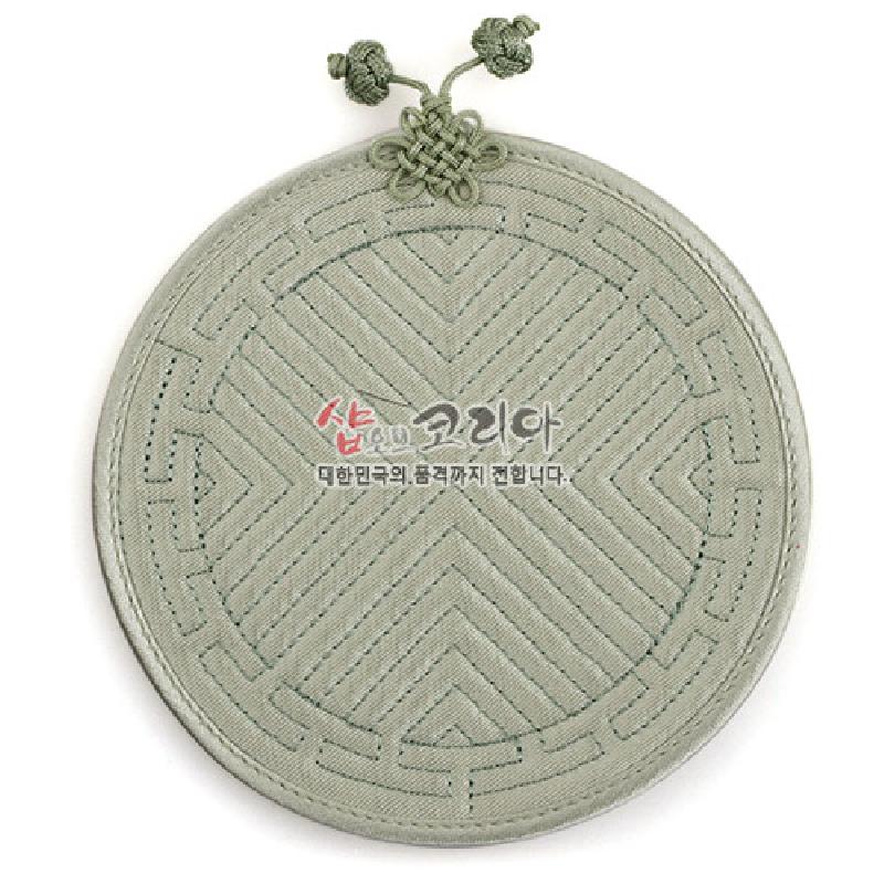 연한 연두색 천 소재에 누비 기법으로 기하학 문양을 넣고 상단에 전통 매듭 장식을 더한 원형 컵받침.