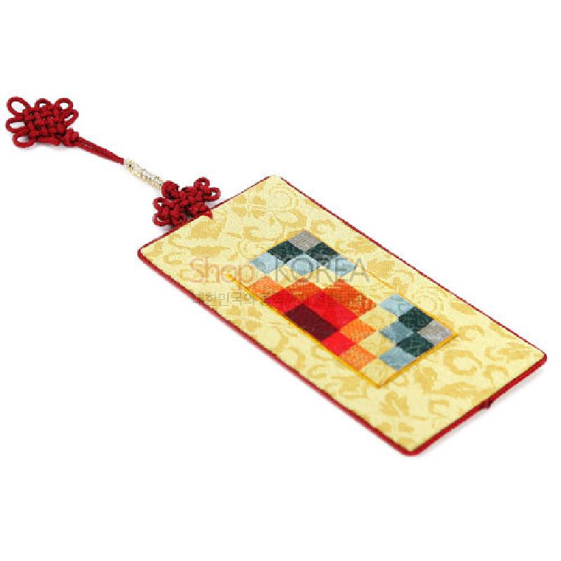 황색 비단 바탕에 다채로운 조각보 패턴과 붉은 전통 매듭 장식이 어우러진 책갈피.