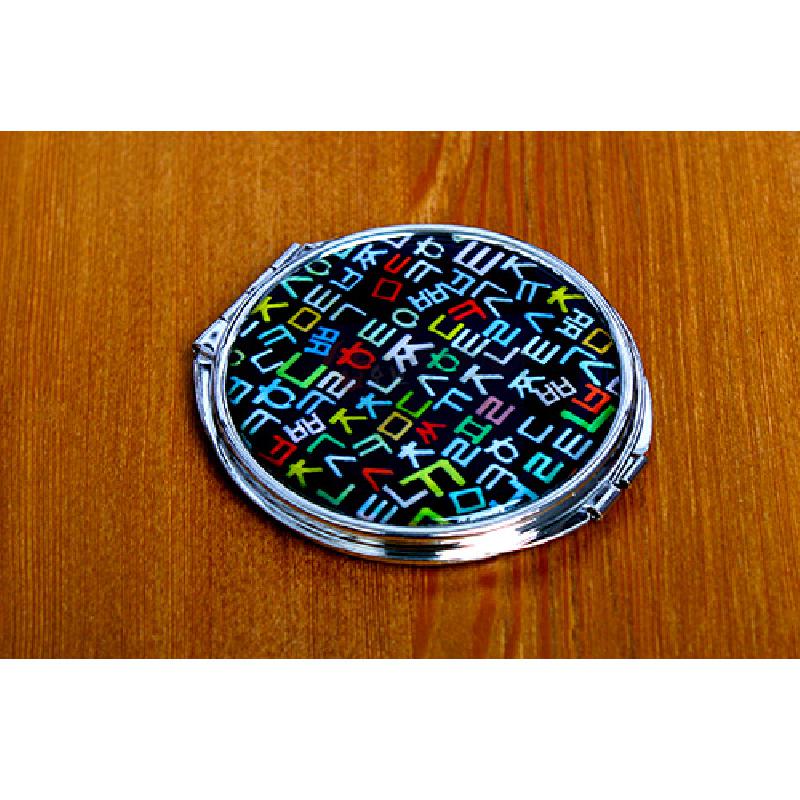 검은 바탕 위에 다채로운 색상의 훈민정음 자음 문양을 입힌 금속 테두리 원형 손거울. 검은 바탕 위에 다채로운 색상의 훈민정음 자음 문양을 입힌 금속 테두리 원형 손거울.