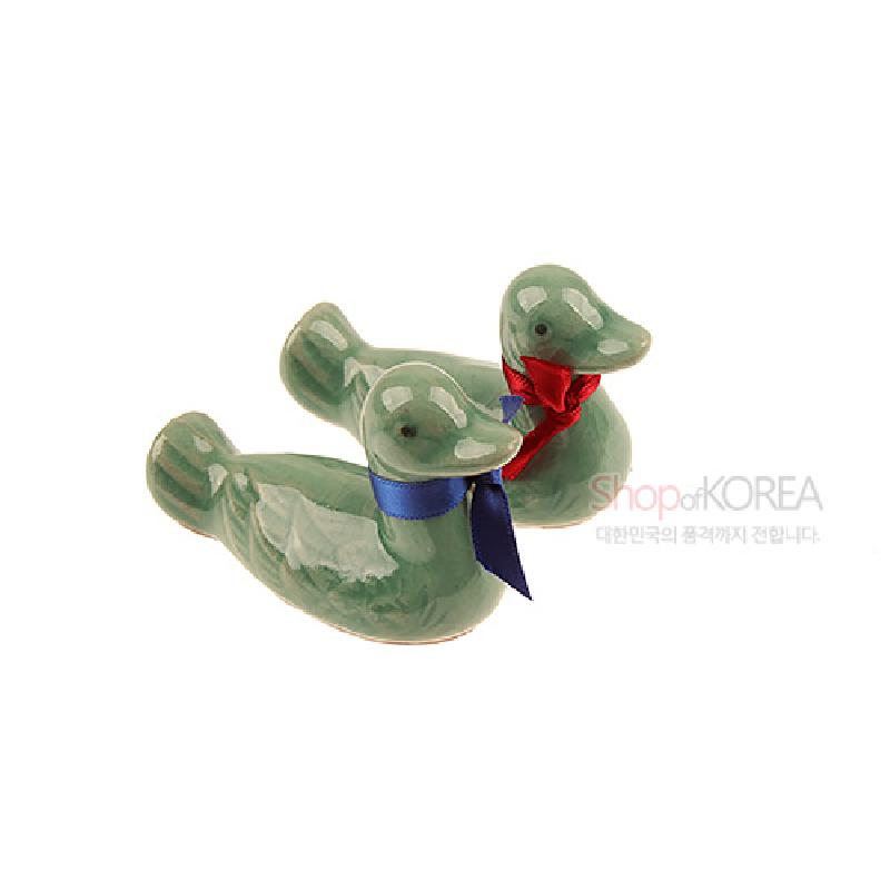 청자 재질의 원앙 형상 수저받침, 유약 광택과 청록색 색조, 붉은색·푸른색 리본 장식이 특징인 구성.