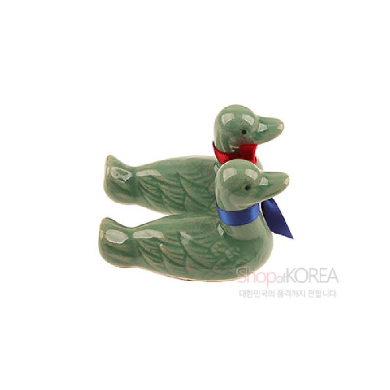 청자 재질의 원앙 형상 수저받침, 비취색 유약과 붉은색·푸른색 리본 장식이 특징인 공예품.